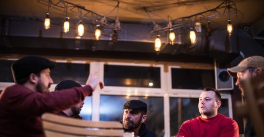 Group of adult men sitting in the bar drinking beer and talking.