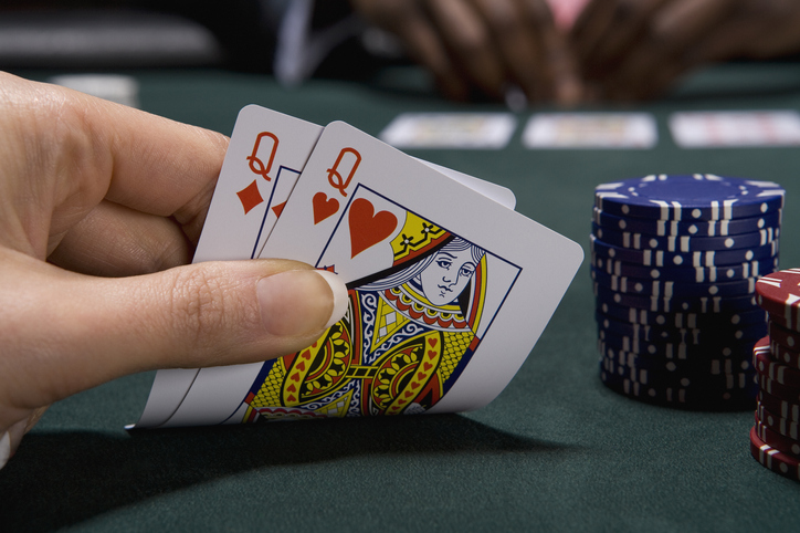 A person skillfully holding a pair of playing cards on a table.