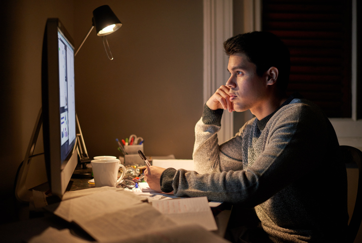 A young man overcoming challenges while working on his computer at night.