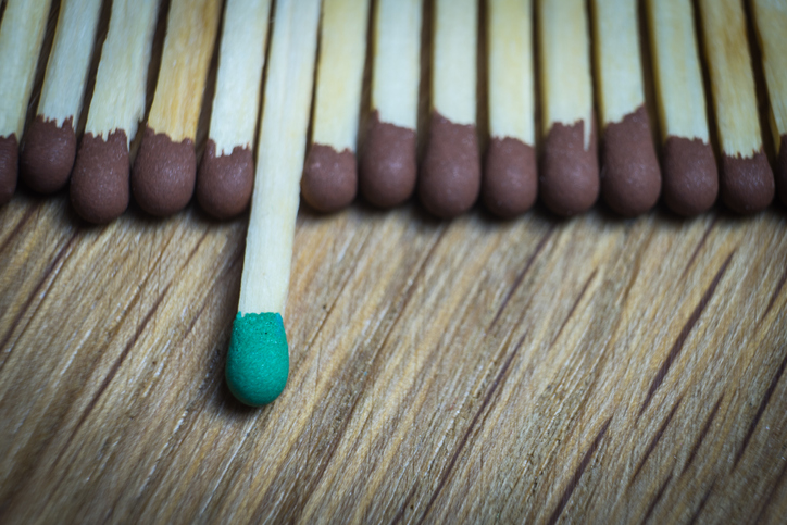 A group of matches with a green one in the center.