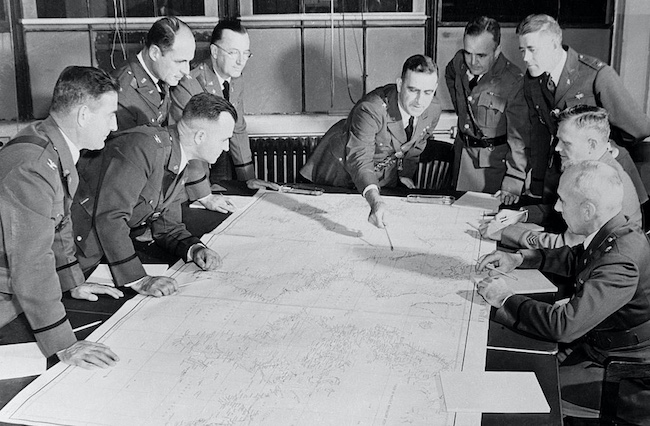 A group of military men in uniform consulting a map.