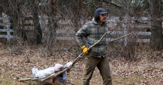 A man using a travois to transport sticks.