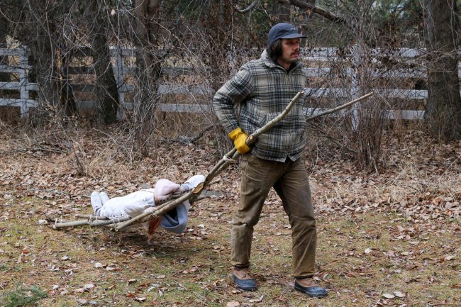 A man using a travois to transport sticks.