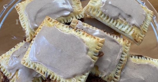 A plate of homemade pastries with chocolate icing on top.
