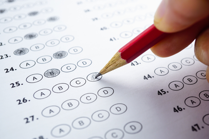 A person uses a pencil to decide on a test sheet.