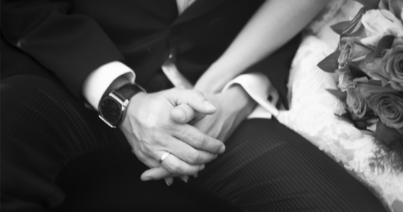 A perfect black and white photo of a bride and groom holding hands.