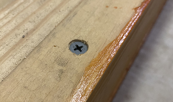 A close-up of a screw on a piece of wood with a countersink.