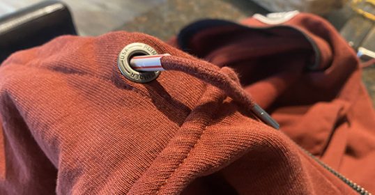 A close up of a red hoodie with a zipper can be rethread in less than 60 seconds.