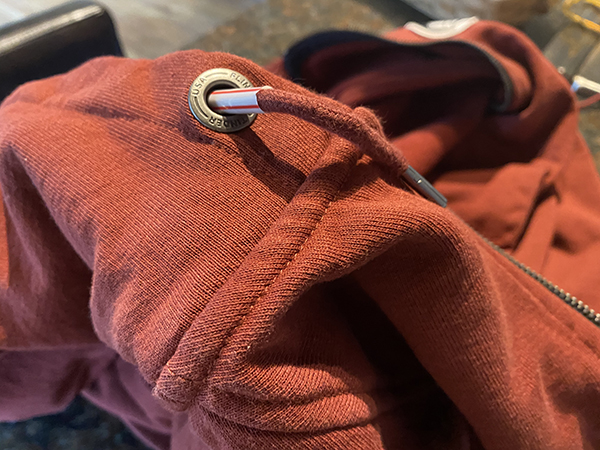 A close up of a red hoodie with a zipper can be rethread in less than 60 seconds.