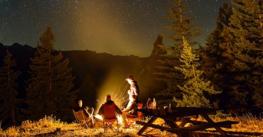 A group of people sitting around a campfire at night, sharing stories and making friends.