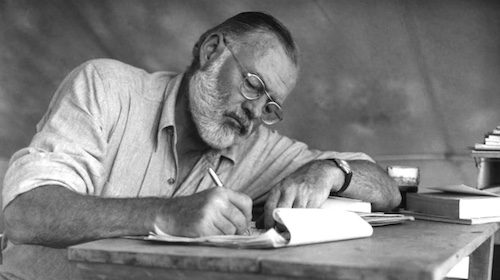 An author sitting at a table writing a book.