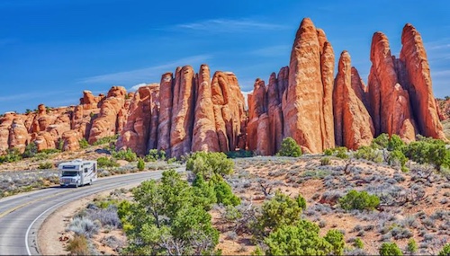 An RV embarking on the Ultimate Road Trip with red rock formations in the background.