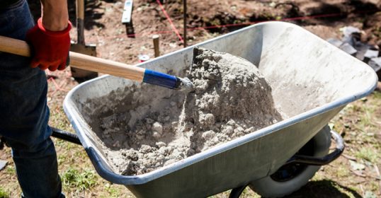 A man pouring concrete into a wheelbarrow in this Beginner's Guide.