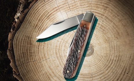 A handy knife is resting on a piece of wood.