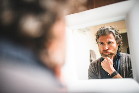 A man podcasting his self-reflection in front of the mirror.
