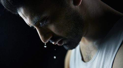 A man with a tear on his face, sweaty and emotional.