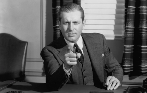 A man quickly pointing his finger at a desk.