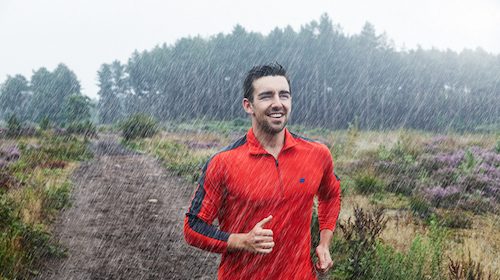 A man jogging in the rain for exercise.