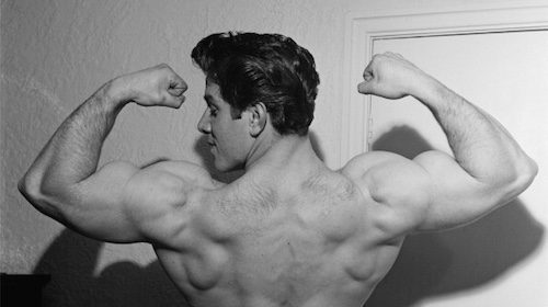 A black and white photo of a man showcasing his muscles for a podcast.