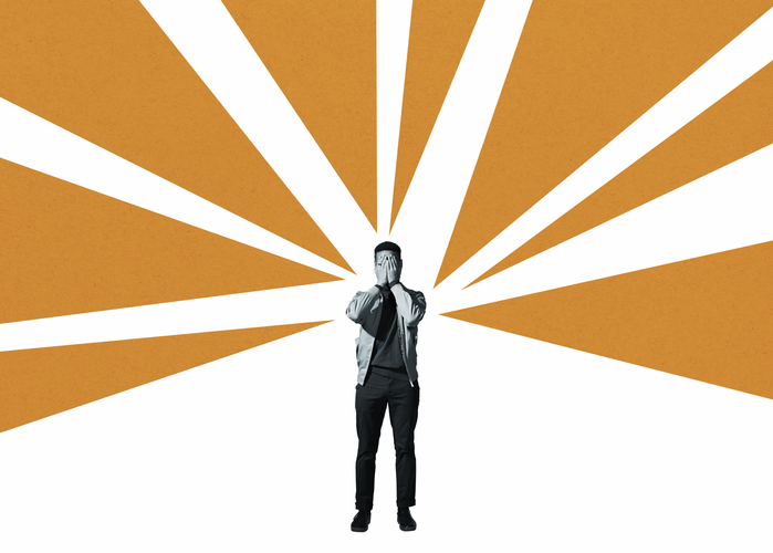A man standing in front of a bright orange sunburst.