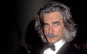 A man in a tuxedo with long hair and mustache.
