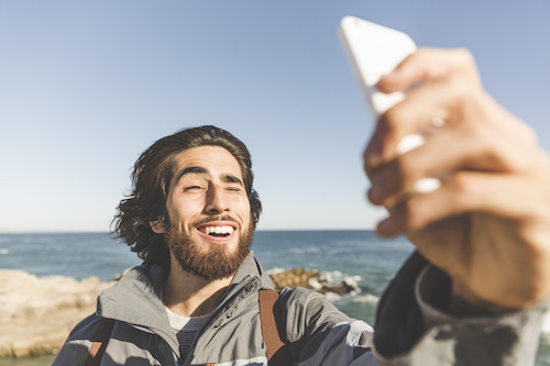 A man is taking a selfie on the beach.