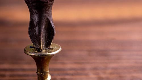 A brass screw on top of a wooden table prevents stripped screws.