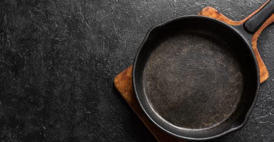 A cast iron skillet on a dark background.