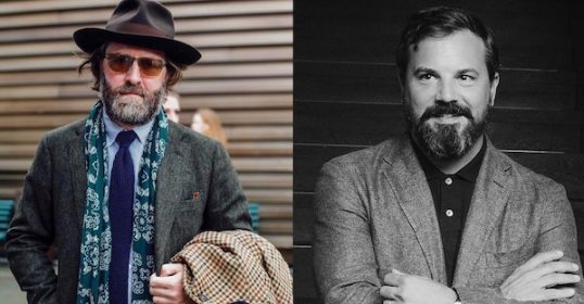 Two men - one in a hat, the other with a beard - are podcast hosts who are developing their personal uniform.
