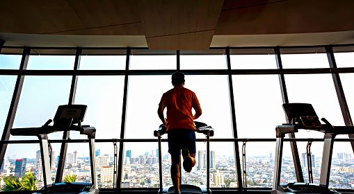 A man is running on a treadmill in a gym, focused on his diet and avoiding decision traps.