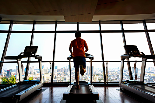 A man is running on a treadmill in a gym, focused on his diet and avoiding decision traps.