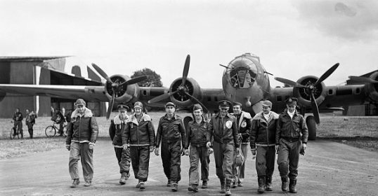 A group of B-17 Pilots walking in front of an airplane from World War II.
