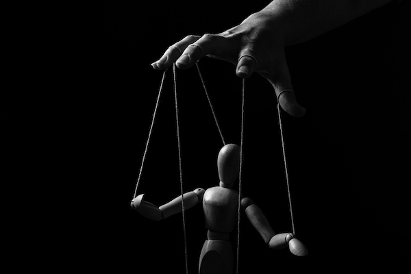 A black and white photo of a hand holding a puppet.