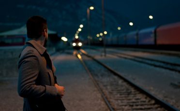 A man standing on a train track at night contemplates his life.