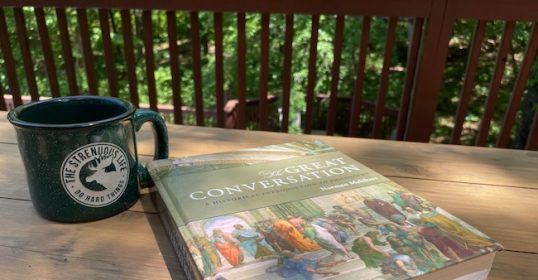 An important textbook sits on a table next to a coffee mug.