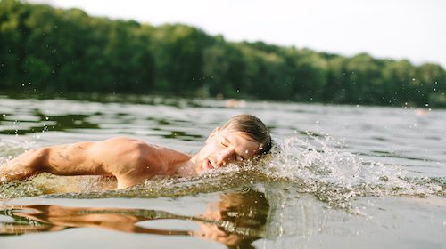A man is swimming in cold water.