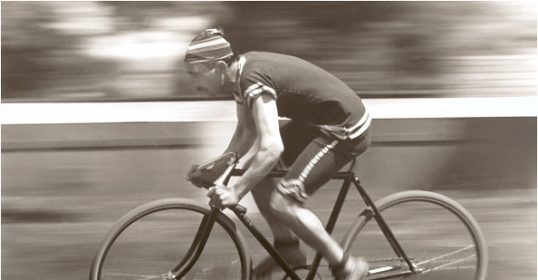 A black and white photo of a man riding a bicycle exudes freedom.