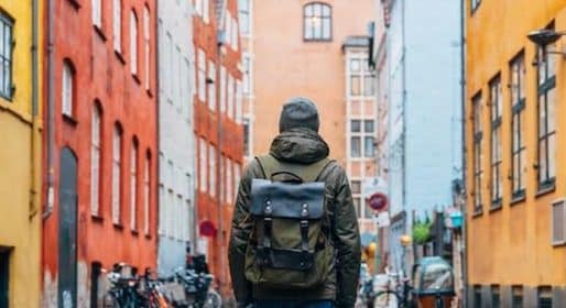 A vagabond with a backpack walking down a cobblestone street in Stockholm, Sweden.
