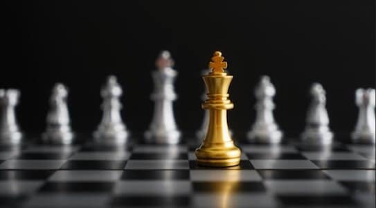Golden king chess piece facing a line of silver pawns on a chessboard, embodying the "Rules of Power" podcast theme.