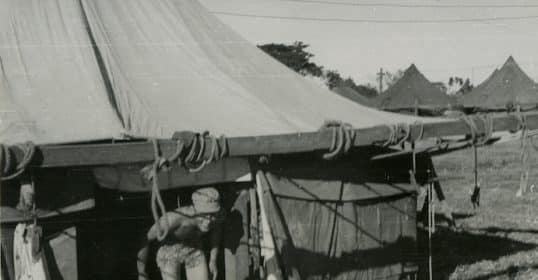 A commando exiting a military tent in a field camp.