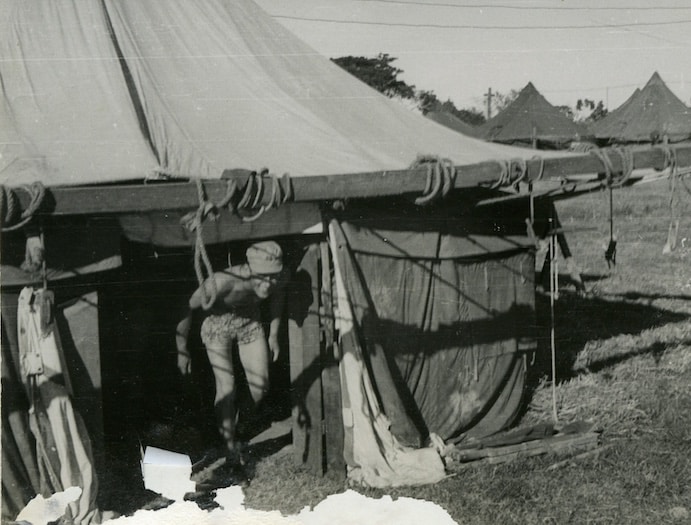 A commando exiting a military tent in a field camp.