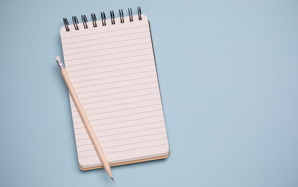 A blank lined notebook for productivity lists with a pencil on a blue background.
