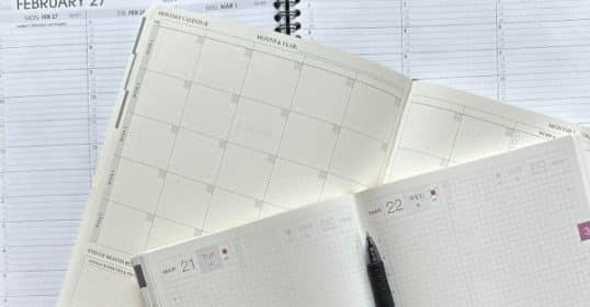 Three of the best open planners with blank pages and a pen on top, suggesting organization and scheduling.