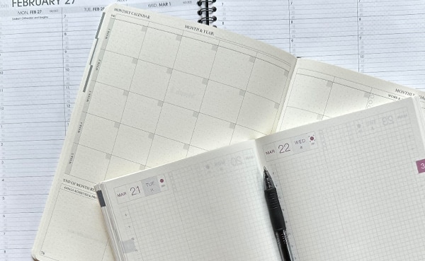 Three of the best open planners with blank pages and a pen on top, suggesting organization and scheduling.