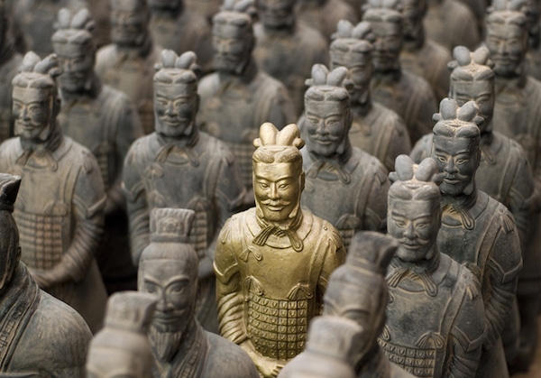 A single terracotta warrior, an essential framework in "The Art of War," stands out in color against rows of monochromatic statues.