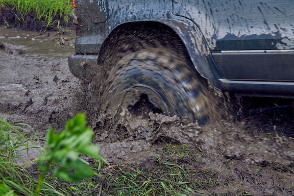 A vehicle's wheel spinning and splashing mud while off-roading, getting unstuck.