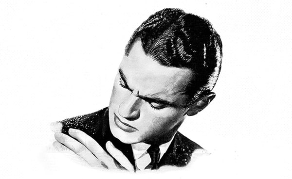 Man in a suit looking thoughtfully at his hand, contemplating how to get rid of dandruff.