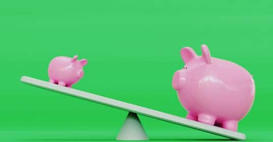 Two piggy banks on a seesaw representing financial strategies, with the larger one on the lower side against a green background.