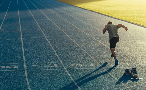 A grown-up's guide to an athlete sprinting on a track field from the starting blocks.