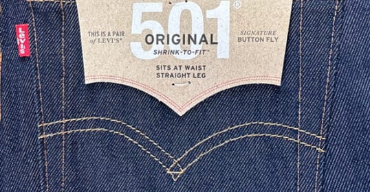 Close-up of the back patch label on a pair of Levi's 501 original shrink-to-fit jeans, serving as a guide to the brand and fit style.